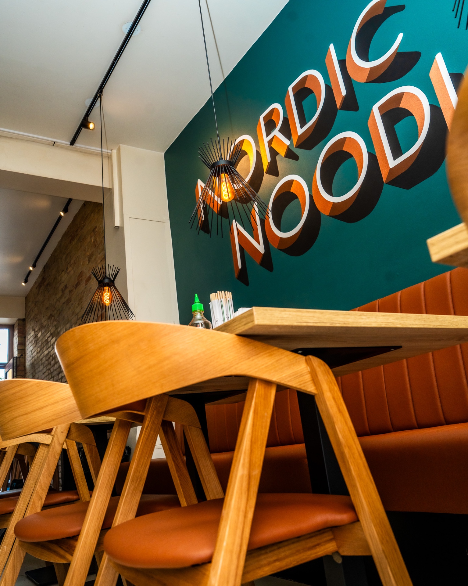 Nordic Noodles restaurant med varme træmøbler og det grønne mural