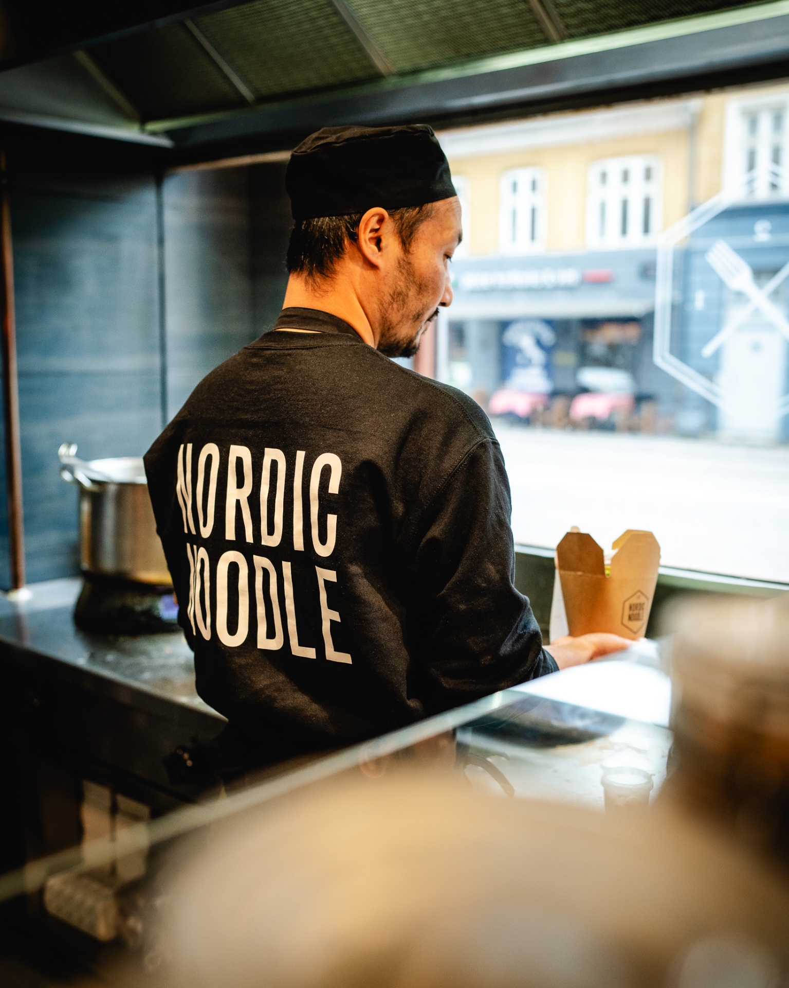 Kok i Nordic Noodle-sweatshirt rækker takeaway-boks ud
